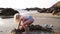 Child girl blonde plays on the beach in the water on the ocean.