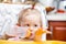 Child girl with bottle with infant formula on kitchen.