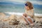 Child girl building stone tower on the beach in summer day