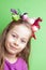 Child girl with colorful birds on her head on green