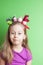 Child girl with colorful birds on her head on green
