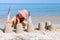 Child girl decorates sand towers, figure with seagull feathers