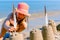 Child girl decorates sand towers, figure with seagull feathers