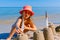 Child girl decorates sand towers, figure with seagull feathers