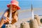 Child girl decorates sand towers, figure with seagull feathers