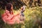 Child girl dressed as fairytale princess playing with doll in summer forest