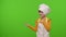 Child girl dressed cook chef baker in apron pointing at left on blank space on chroma key background