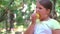 Child girl eating an red apple in a park in nature.