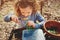 Child girl exploring nature in early spring, looking at first sprouts with loupe.