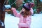 Child girl feeding birds in winter. Bird feeder in snowy garden, helping birds during cold season