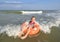 Child girl floatting on orange pool ring on the background of turquoise sea water and waves