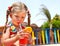 Child girl in glasses and red bikini drink juice.
