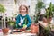 A child girl in a green dress transplants potted flowers in the winter garden. Girl in gardening help transplant flowers