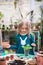 A child girl in a green dress transplants potted flowers in the winter garden. Girl in gardening help transplant flowers