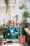 A child girl in a green dress transplants potted flowers in the winter garden. Girl in gardening help transplant flowers