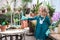 A child girl in a green dress transplants potted flowers in the winter garden. Girl in gardening help transplant flowers