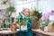 A child girl in a green dress transplants potted flowers in the winter garden. Girl in gardening help transplant flowers