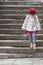 Child girl hat and coat walks stone stairs