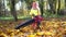 Child girl holding leaf blower and blowing autumn leaves in garden