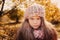 Child girl in knitted scarf and sweater on autumn walk in forest