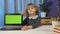 Child girl with laptop looking on green screen at home, online distance lessons children education