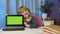 Child girl with laptop looking on green screen at home, online distance lessons children education