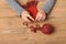 Child girl is learning to knit a scarf. Red wool yarn is on the wooden table. Hand closeup