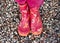 Child girl legs in pink galoshes on stone beach