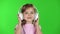 Child girl listens to music through the headphones. Green screen. Slow motion