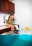 Child girl make mess, flooded kitchen imitating swimming pool, f