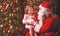 child girl in nightgown sitting on lap of Santa Claus around Christmas tree