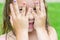 Child girl peeking through her fingers covering her eyes