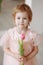 Child girl in a pink dress among tulips in vases