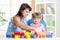 Child girl playing construction set with mother