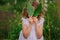 Child girl playing with leaves in summer forest with birch trees. Nature exploration with kids.