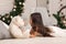 Child girl playing with teddy bear near the Christmas tree