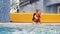 Child girl in the pool in the life jacket sits in the boiling blue water and is preparing to dive