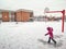 Child girl in red pink jacket sliding on ice road on her feet on schoolyard. Winter fun activity for kids. Candid authentic