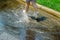 child girl running and jumping in puddles after rain in summer