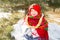 Child girl in Russian pavloposadskie folk scarf on head with floral print and with bunch of bagels on background of snow.