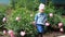 Child girl send air kisses. Garden with peonies and funny baby