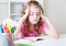 Child girl sitting at desk table learning lessons headacke.Tired  kid