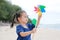 Child girl with a spinning pinwheel on the beach