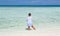 Child girl standing in tranquil, turquoise beautiful inviting ocean and feeding the fish