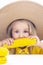 Child girl in a straw hat in yellow clothes eats corn,