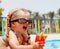 Child girl in sunglasses and red bikini drink.