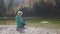 Child girl throwing stones into the mountain river