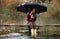 Child girl with umbrella sits on wooden bridge and smiles in rain.