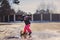 Child girl in waterproof pants jumping in puddle on winter walk