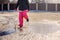 Child girl in waterproof pants jumping in puddle on winter walk